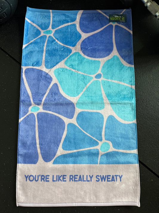 Blue and purple towel with floral geometric pattern and text on a black surface