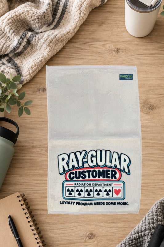 Cream Ray-gular Customer towel laid flat on a wood table beside a knit blanket, water bottle, tumbler and notebook.