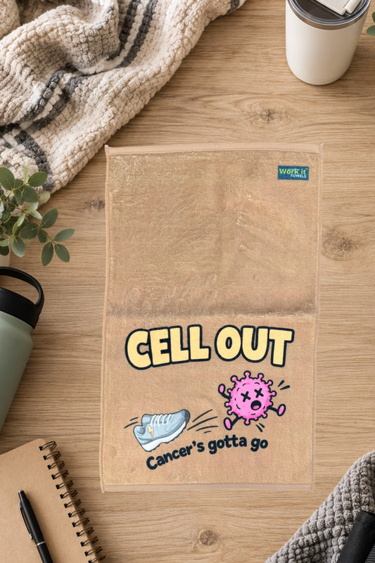 Tan Cell Out towel laid flat on a wood table beside a knit blanket, water bottle, tumbler and notebook.