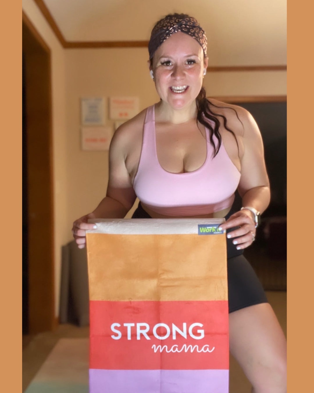Fit mom holding warm colored 'strong mama' gym towel design