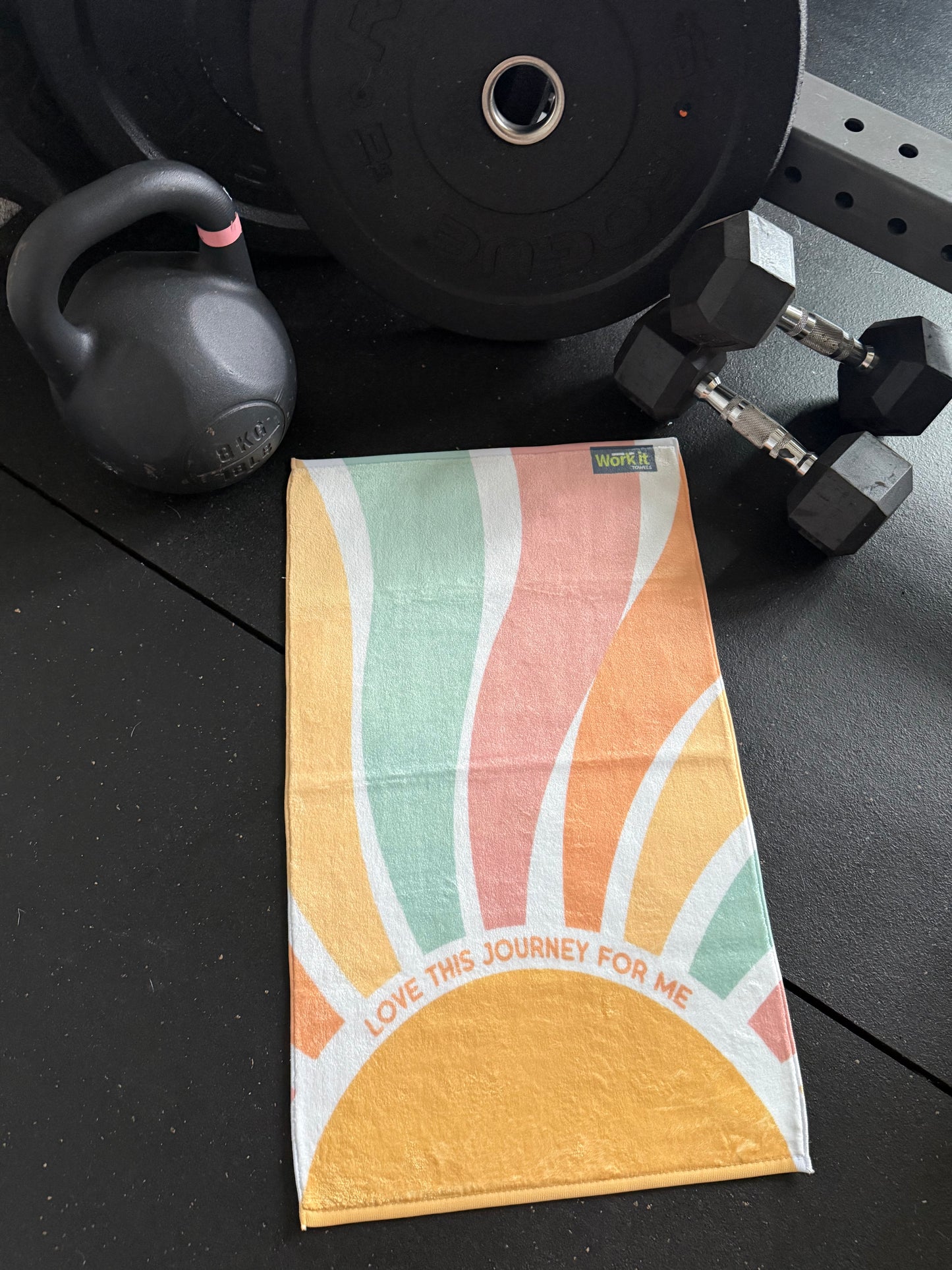 Colorful towel with sun ray abstract design on a black surface with gym equipment