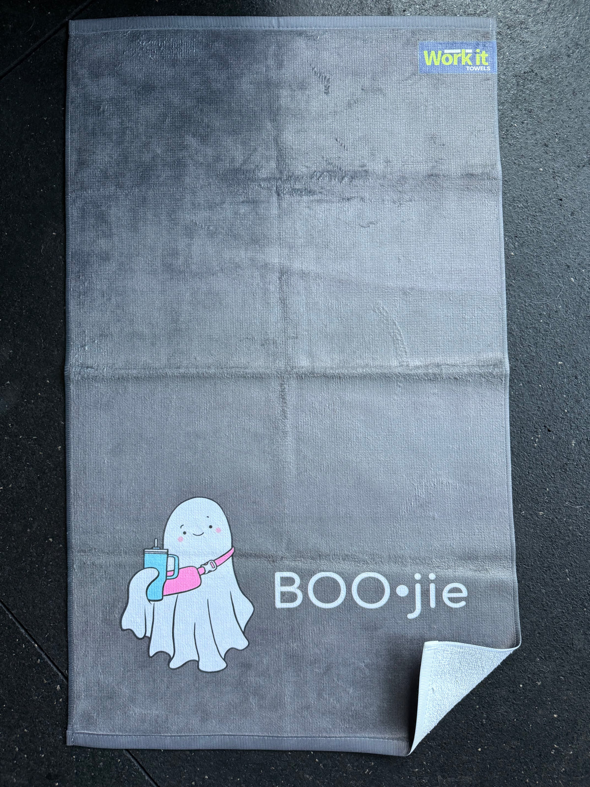 Gray towel with a ghost design and 'BOO•jie' text on a dark surface