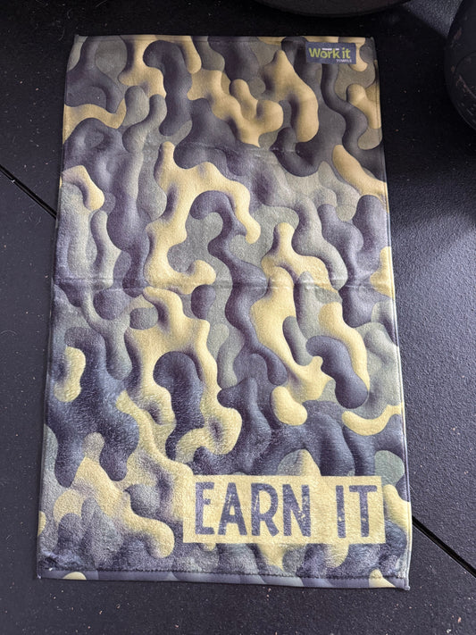 Camouflage-patterned pouch with 'EARN IT' text on a black surface