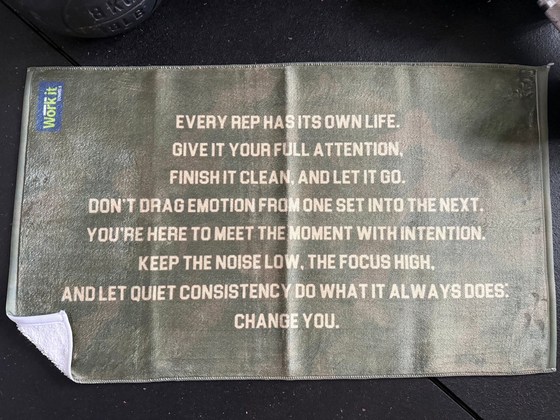 Motivational quote on a black surface with a visible brand logo.