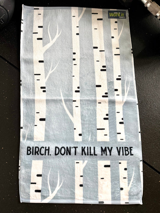 Tea towel with birch tree design and text on a dark surface