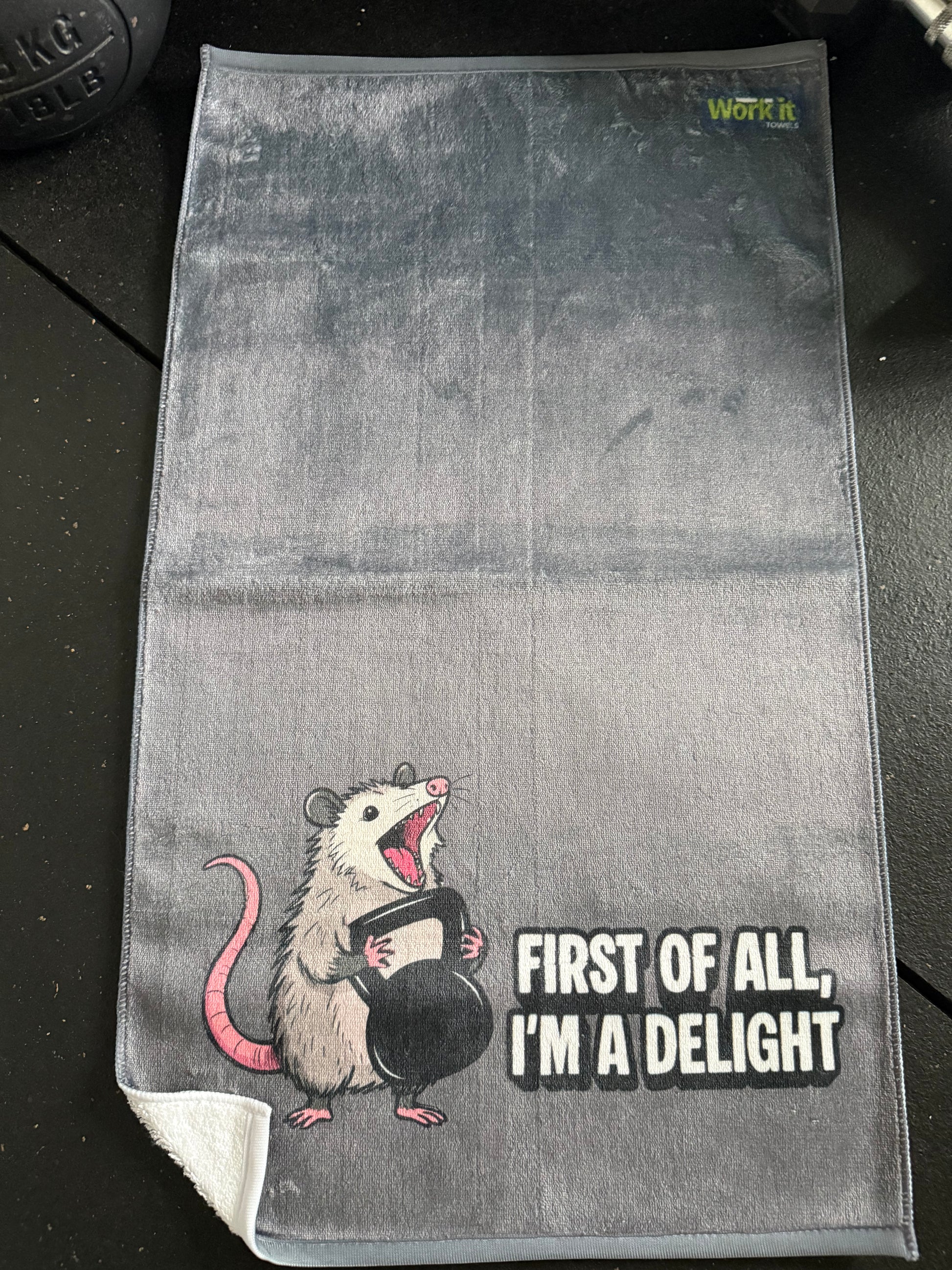 Gray towel with an opossum illustration and text on a dark surface