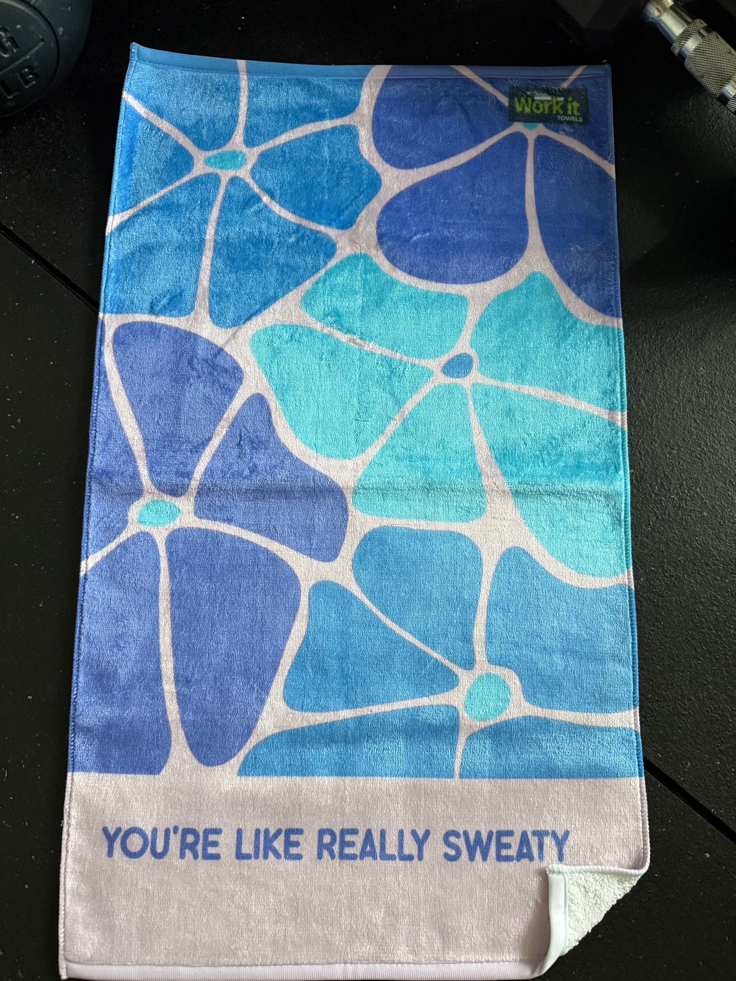 Blue floral patterned towel with text on a black surface
