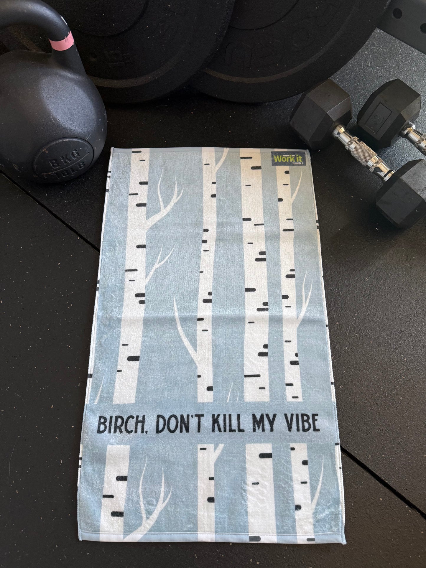 Textile with birch tree design and text 'Birch. Don't Kill My Vibe' on a dark surface with fitness equipment.