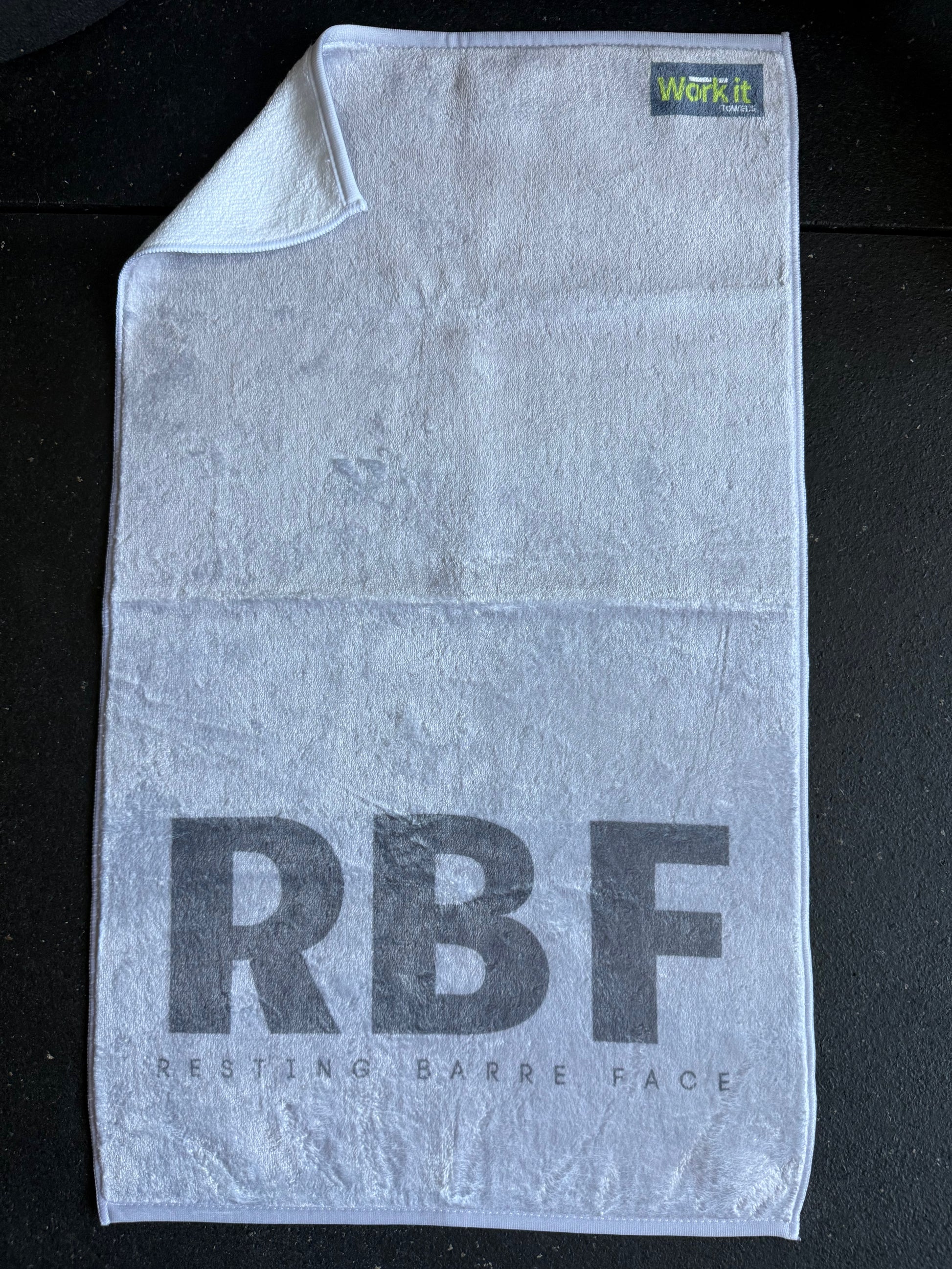Gray towel with 'RBF Resting Barre Face' text on a black background