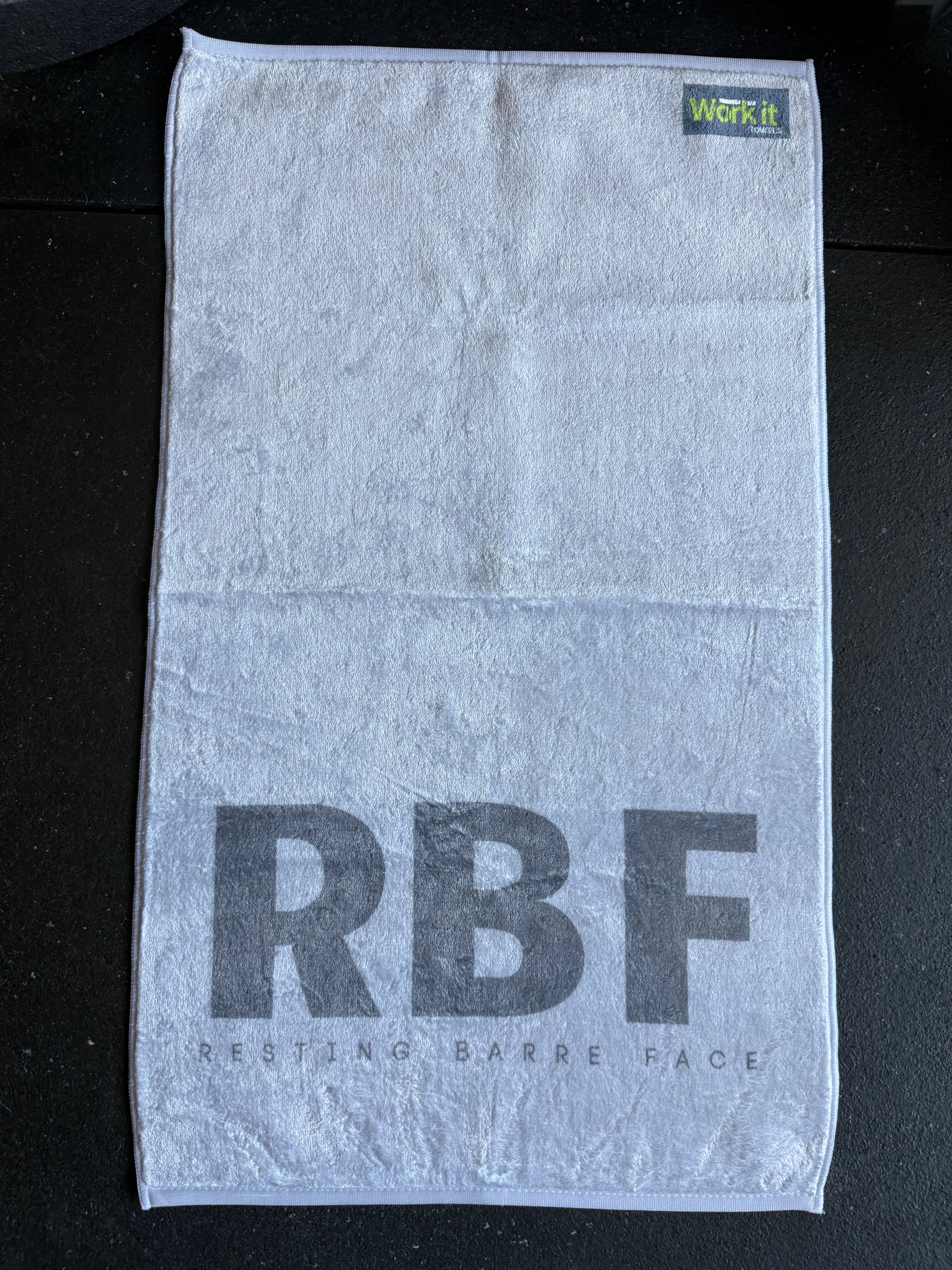 Gray towel with 'RBF' and 'Work It' text on a black background