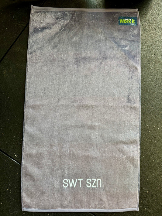 Gray towel with 'SWT SZN' text on a dark surface