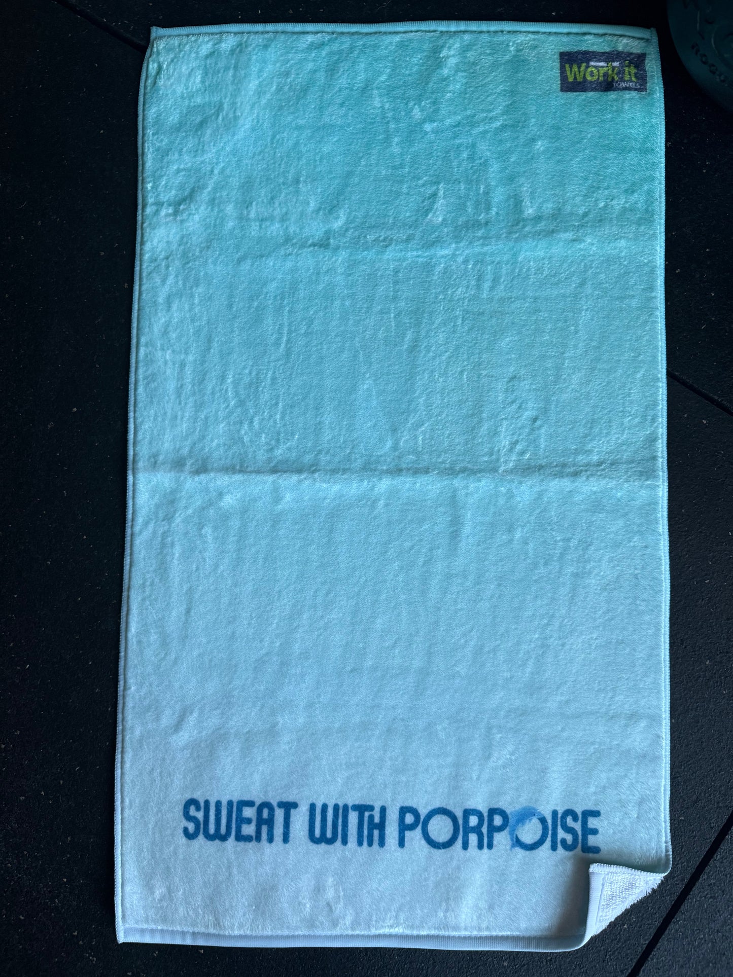 Light blue towel with 'Sweat with Porpoise' text on a black background