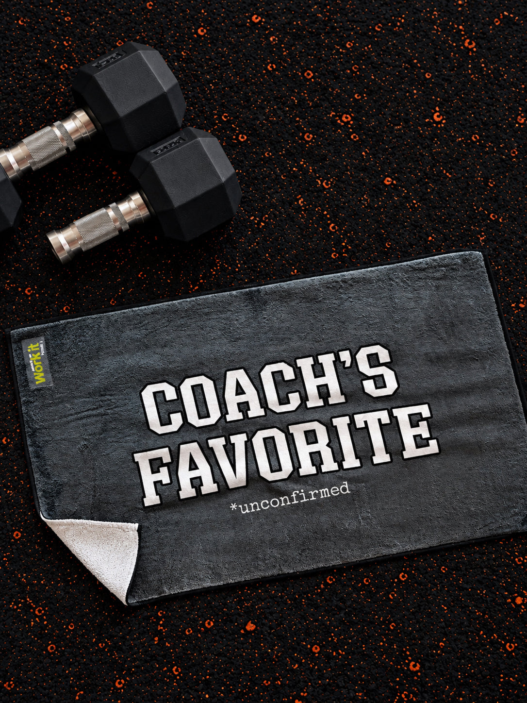 plush grey towel with 'coach's favorite unconfirmed' in white font on gym floor