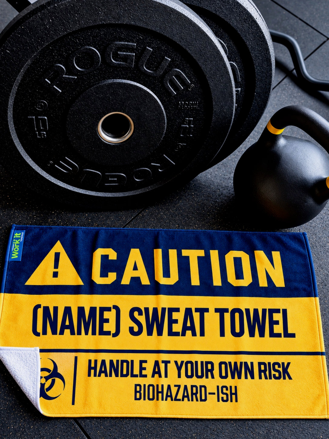 Personalized Work It Towels gym sweat towel with bold yellow and black CAUTION design, customized with “Jay's Sweat Towel” and “Handle at Your Own Risk” warning, with lower left corner exposing the white terry cloth underside displayed on a gym floor beside weight plates and a kettlebell.