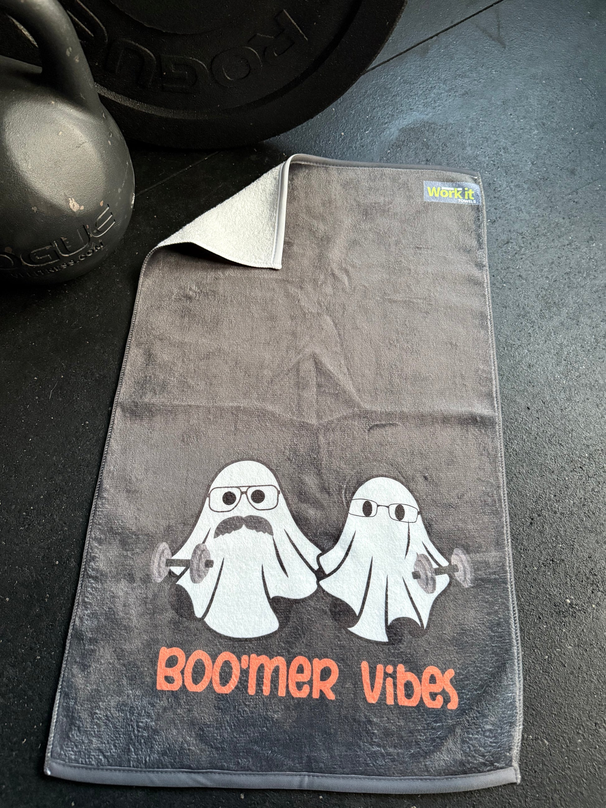 Gray towel with a graphic design and 'Boomer Vibes' text on a dark surface