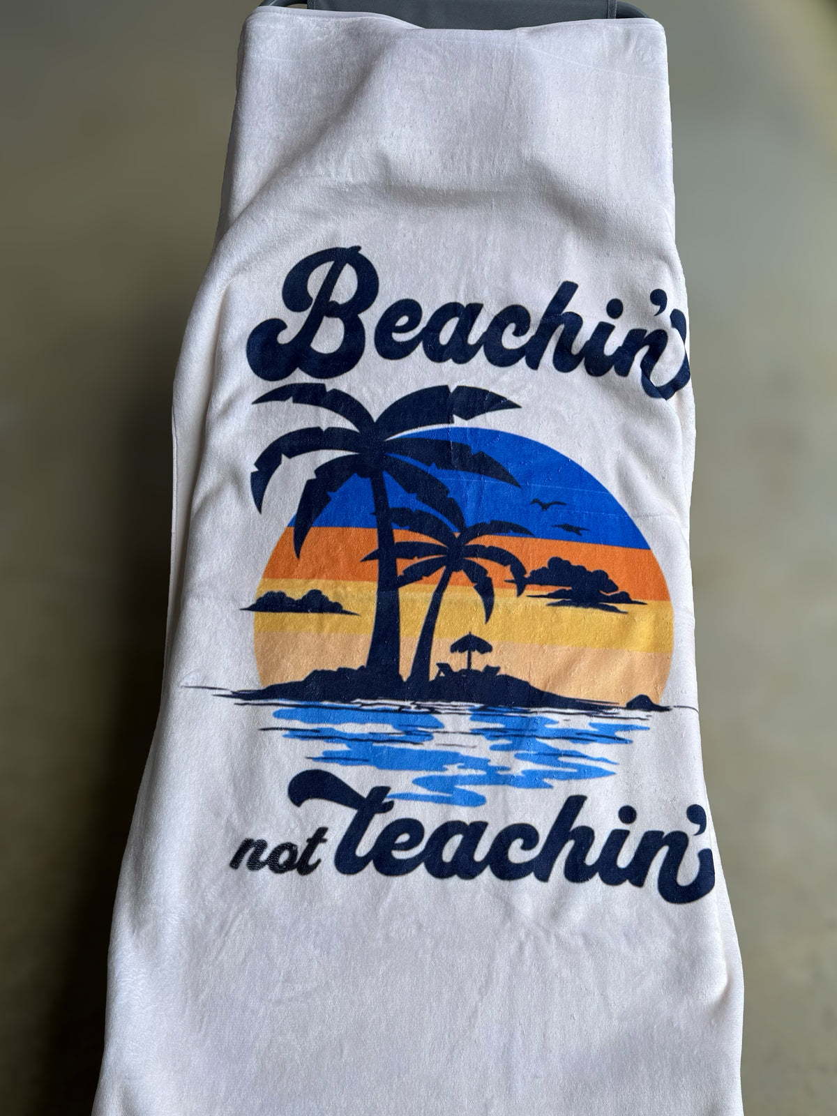'beachin not teachin' with a sunset with palm trees design on a plush cream beach towel
