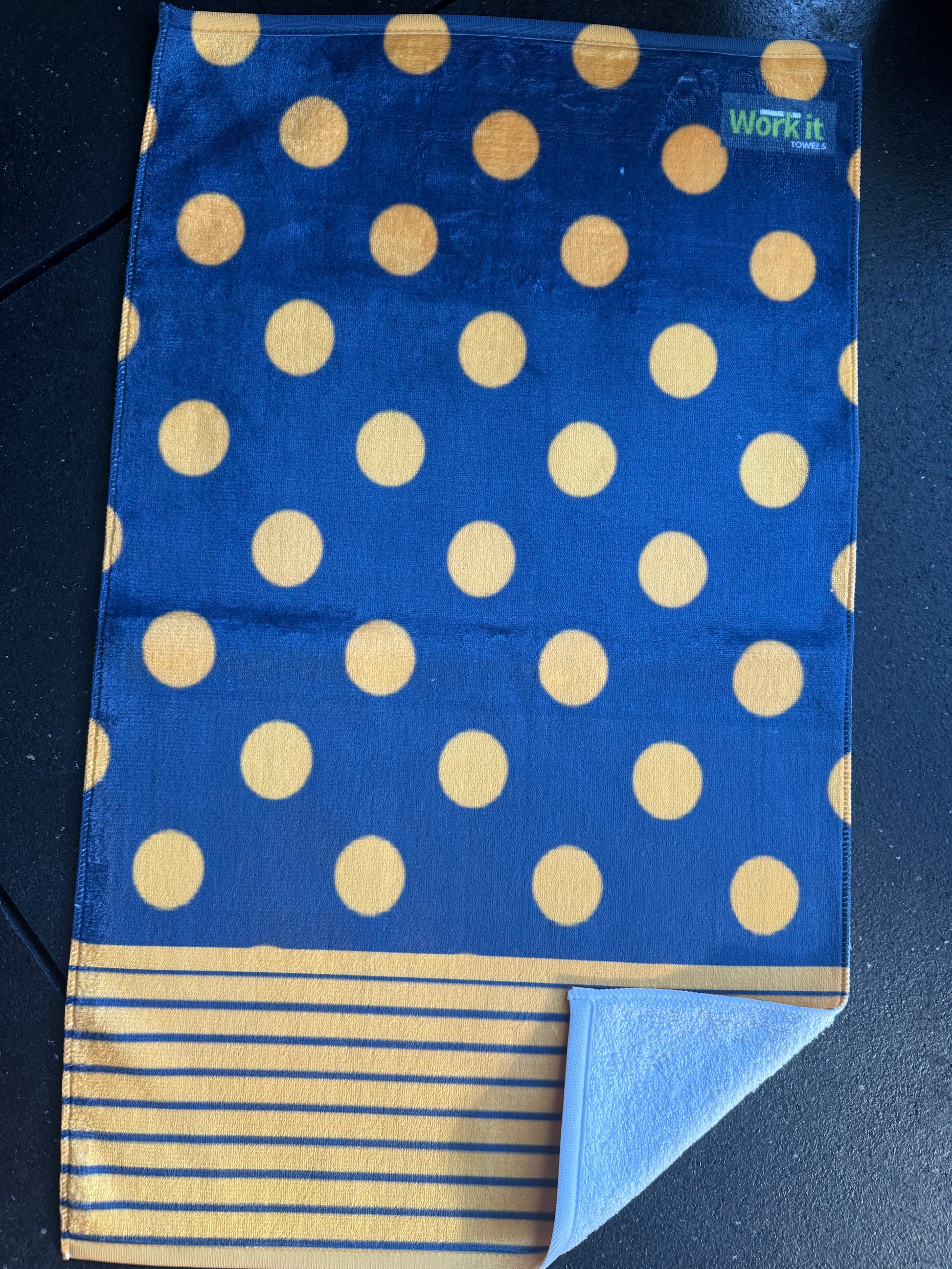 Blue towel with gold polka dots and stripes on a dark background