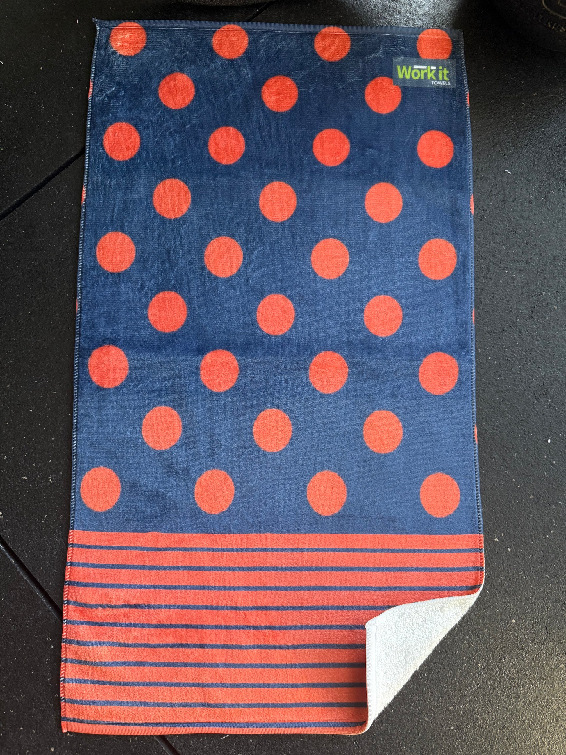 Towel with red polka dots and stripes on a dark surface