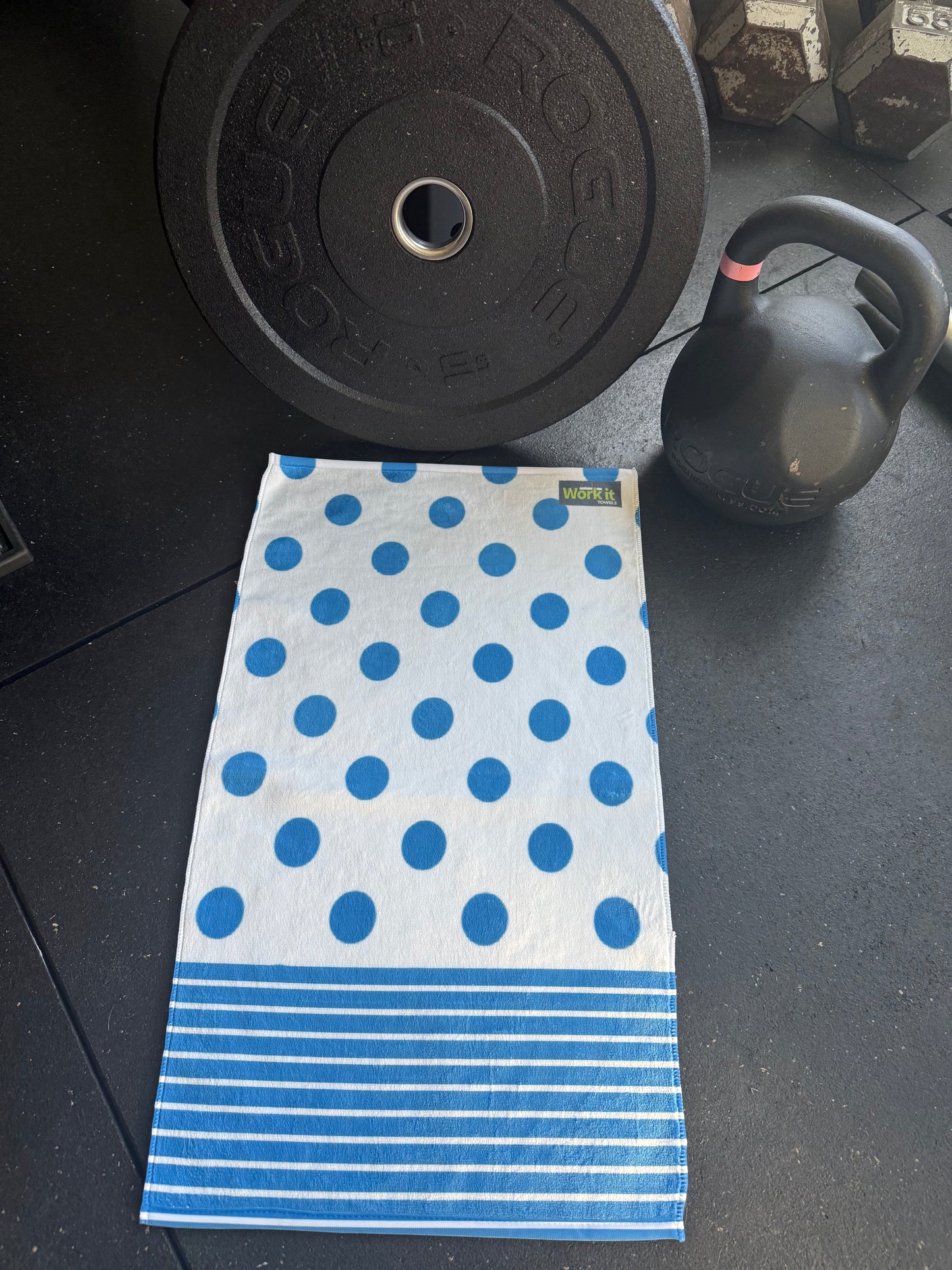 Blue and white polka dot towel on a black surface with gym equipment.