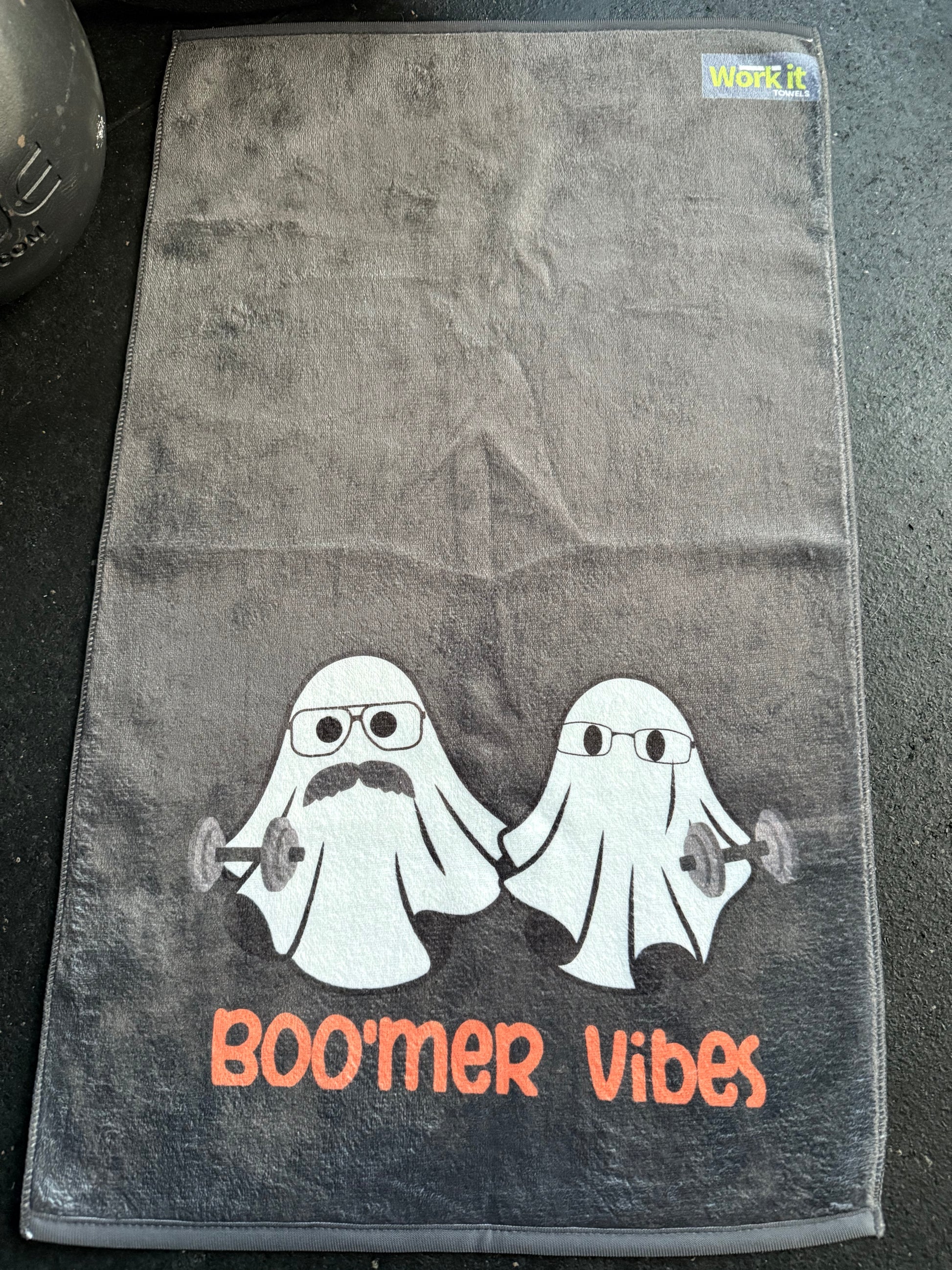 Gray towel with a cartoon character and 'Boomer Vibes' text on a dark surface