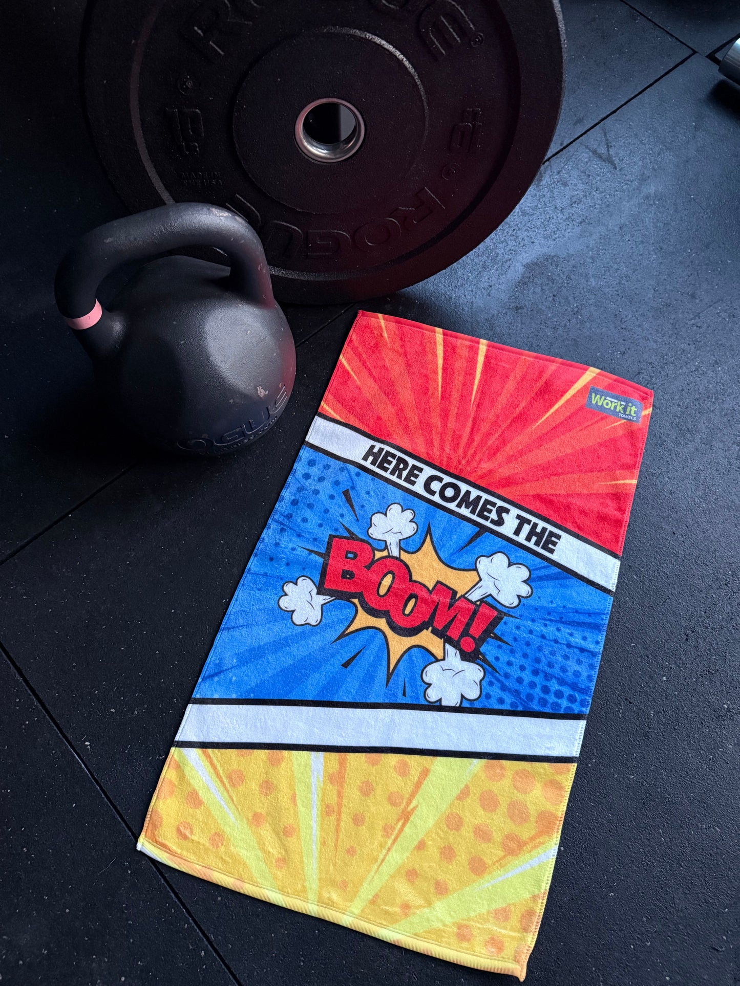 Colorful towel with comic book design on a gym floor with weights