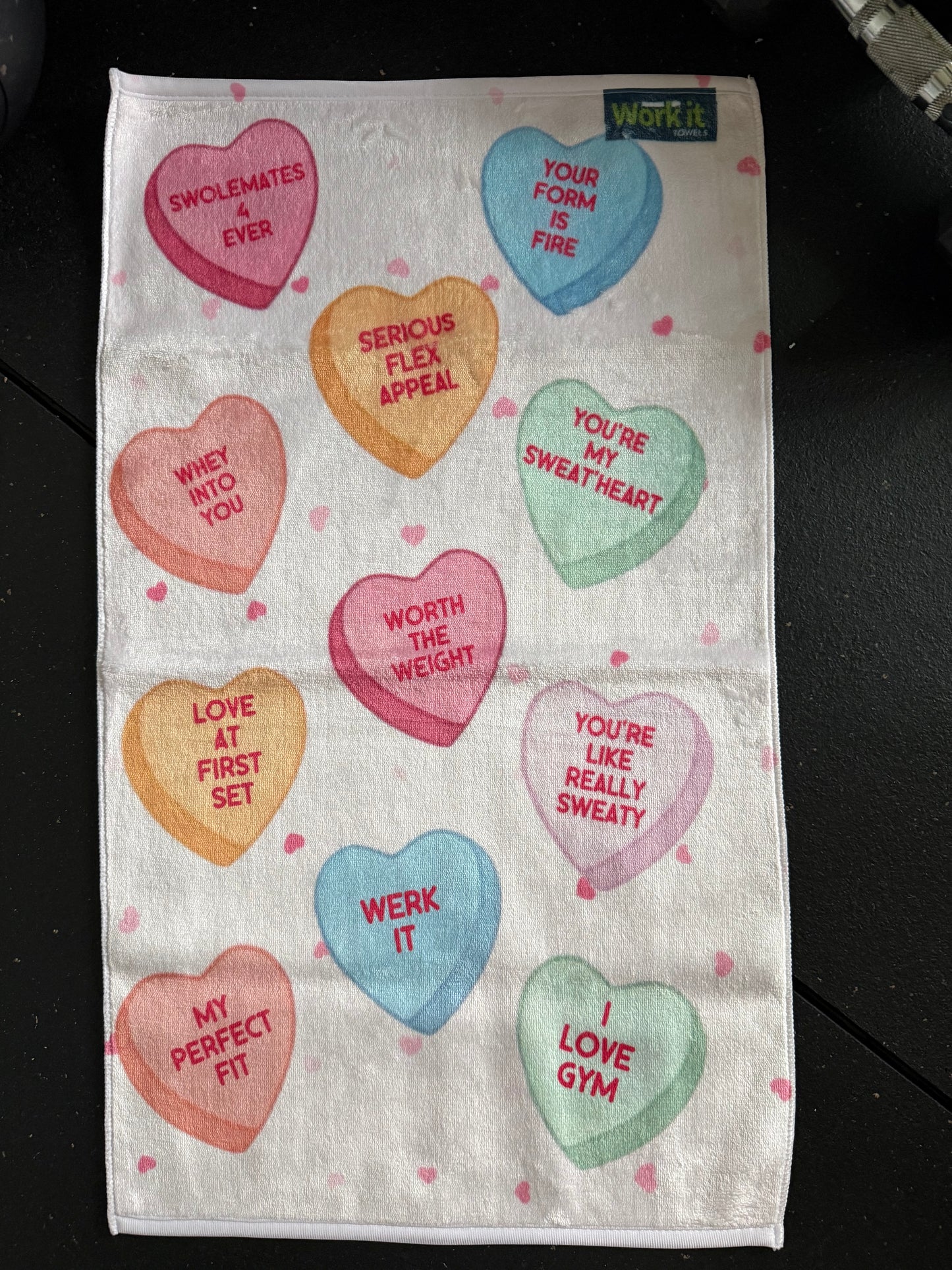 Towel with colorful heart-shaped text on a black background
