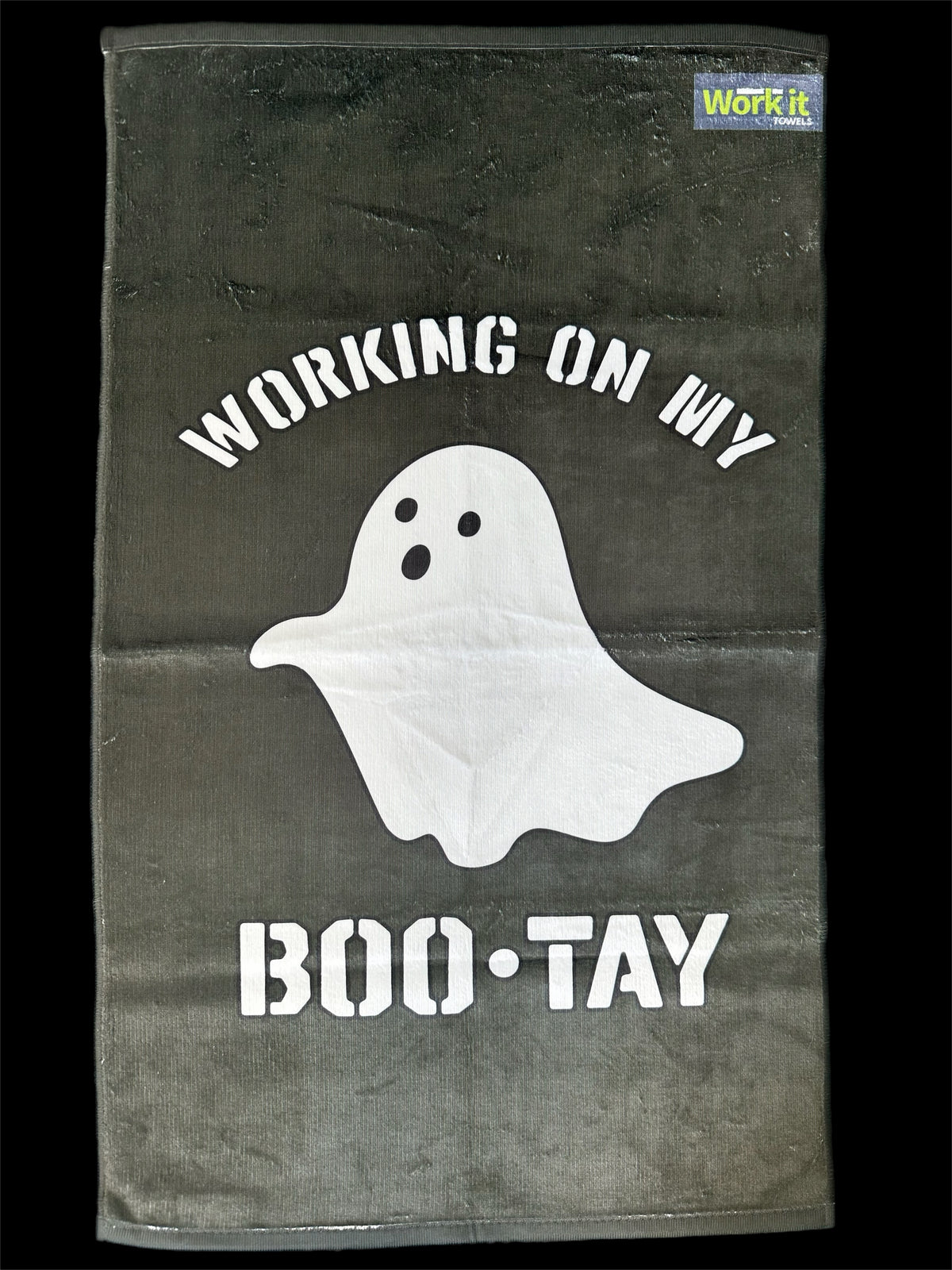 Towel with ghost graphic and text 'Working on my BOO-TAY' on a dark background
