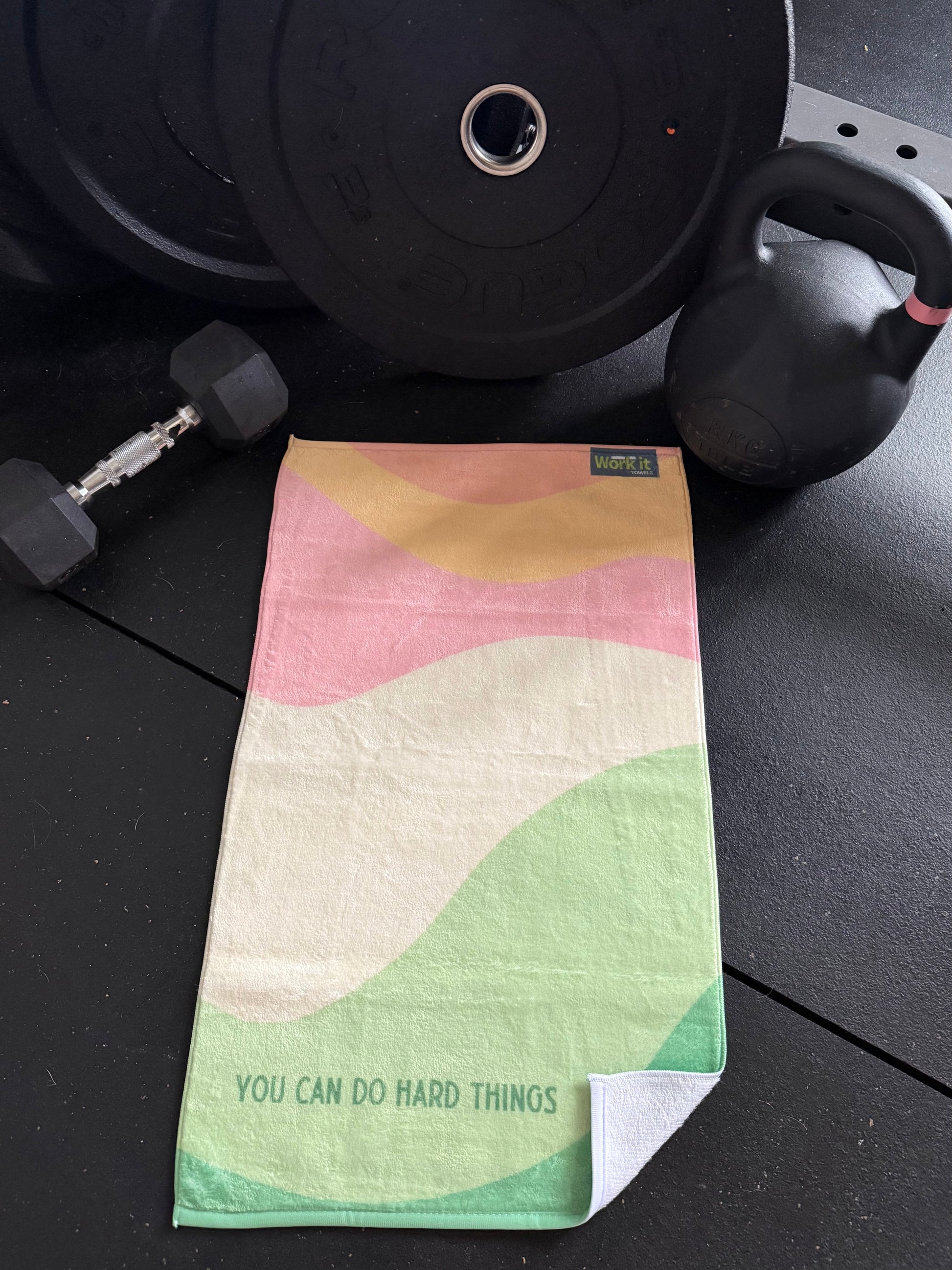 Colorful towel with motivational quote on a gym floor with weights in the background