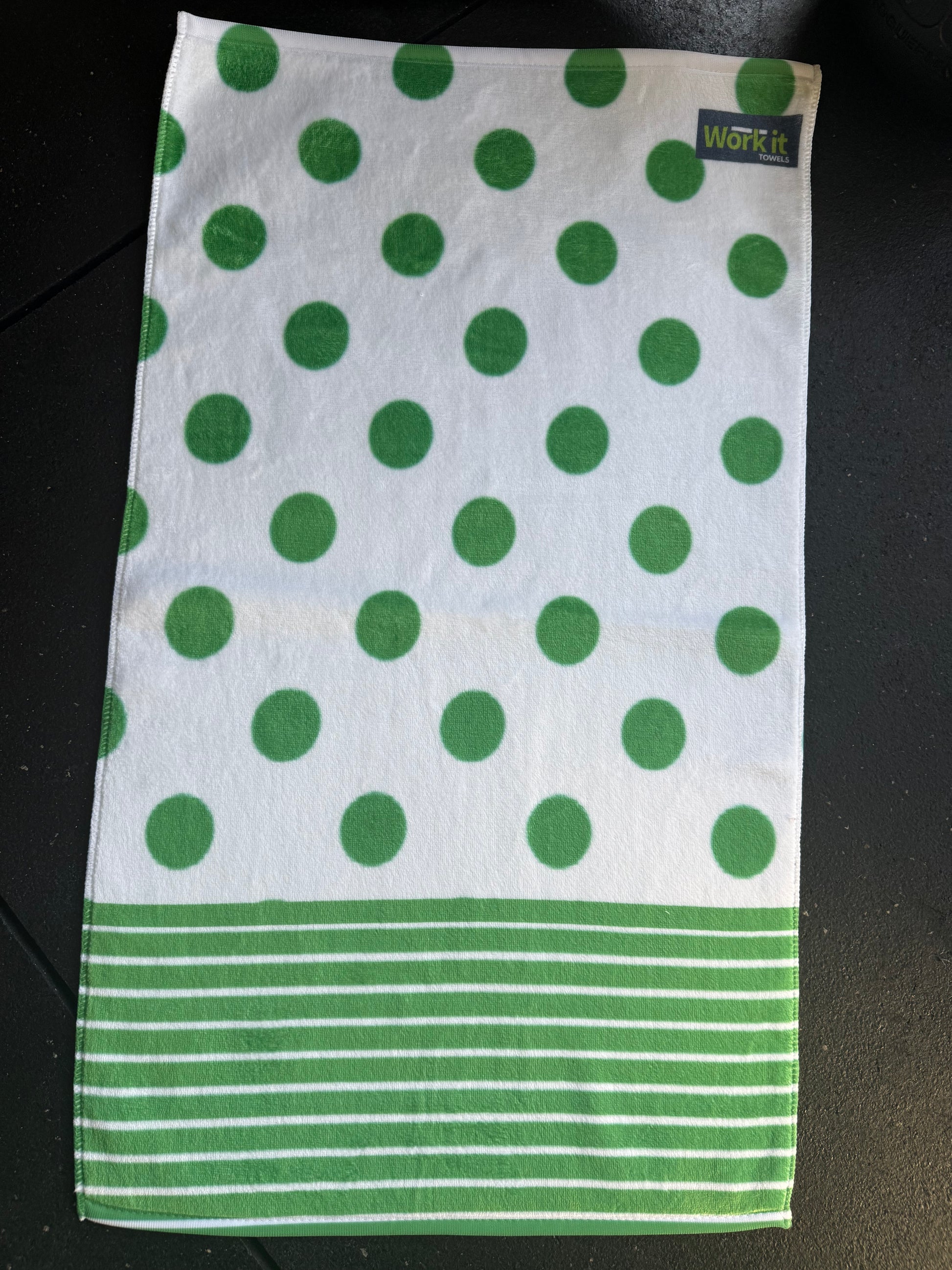 Green and white polka dot towel with a brand label on a black surface