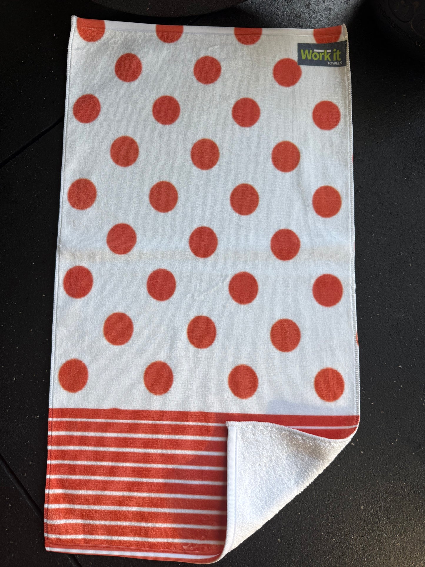 Folded towel with red polka dots and stripes on a dark surface