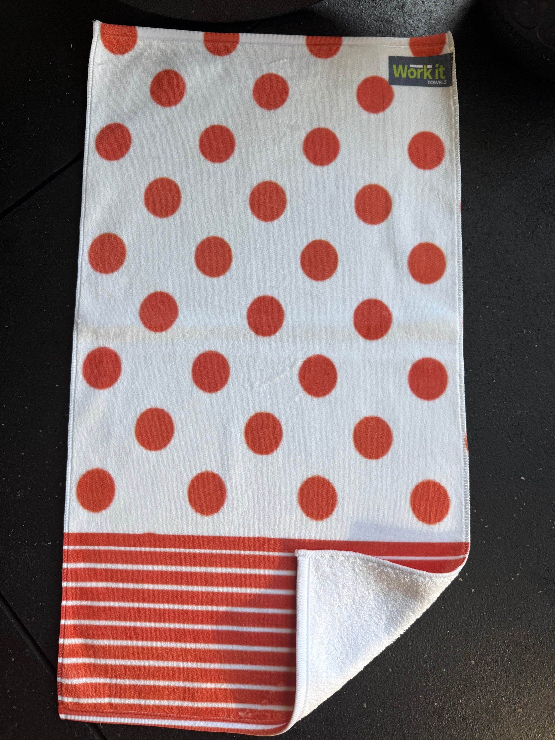 Folded towel with red polka dots and stripes on a dark surface