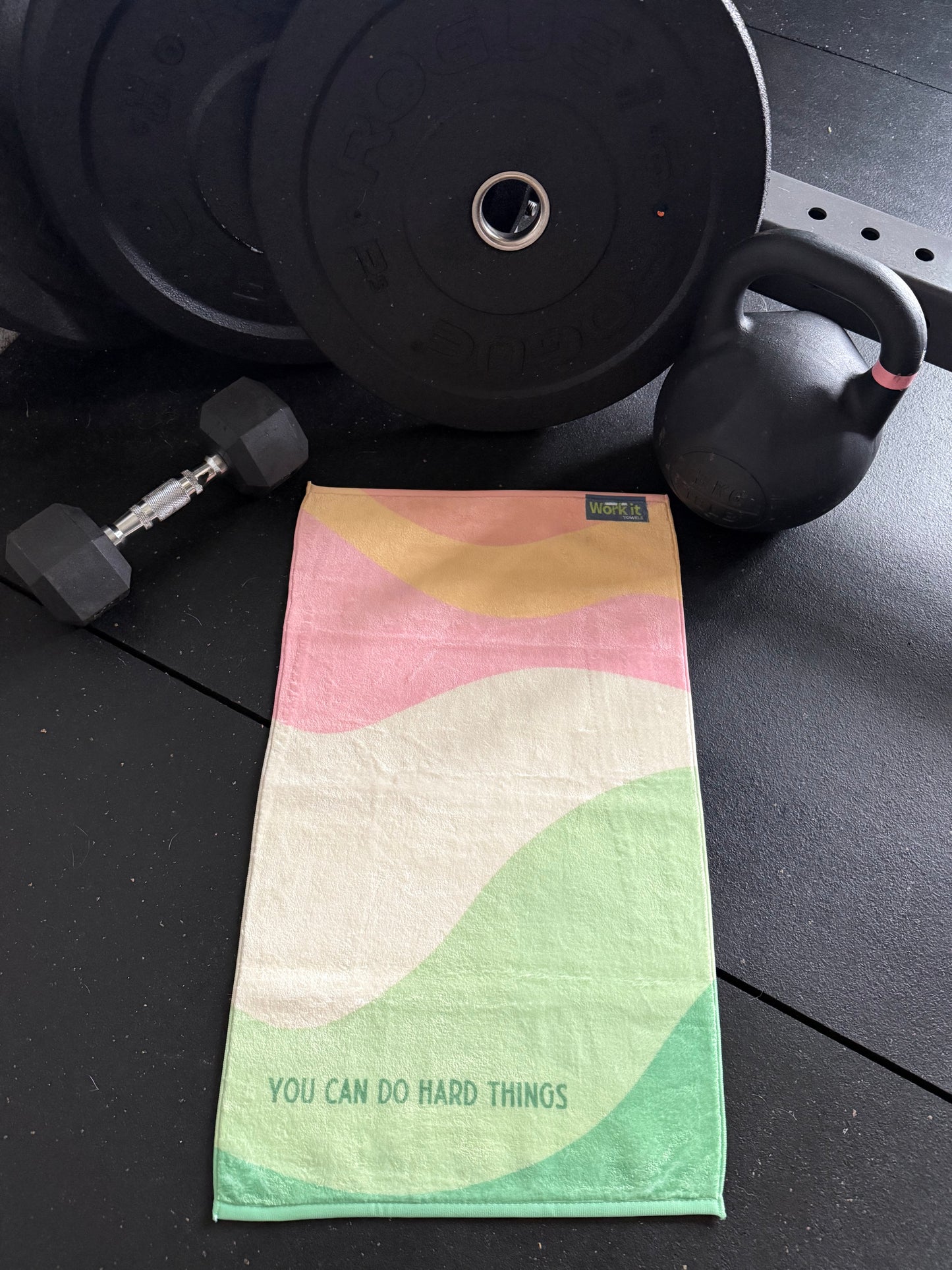 Stack of weights with a colorful pastel towel on a black surface