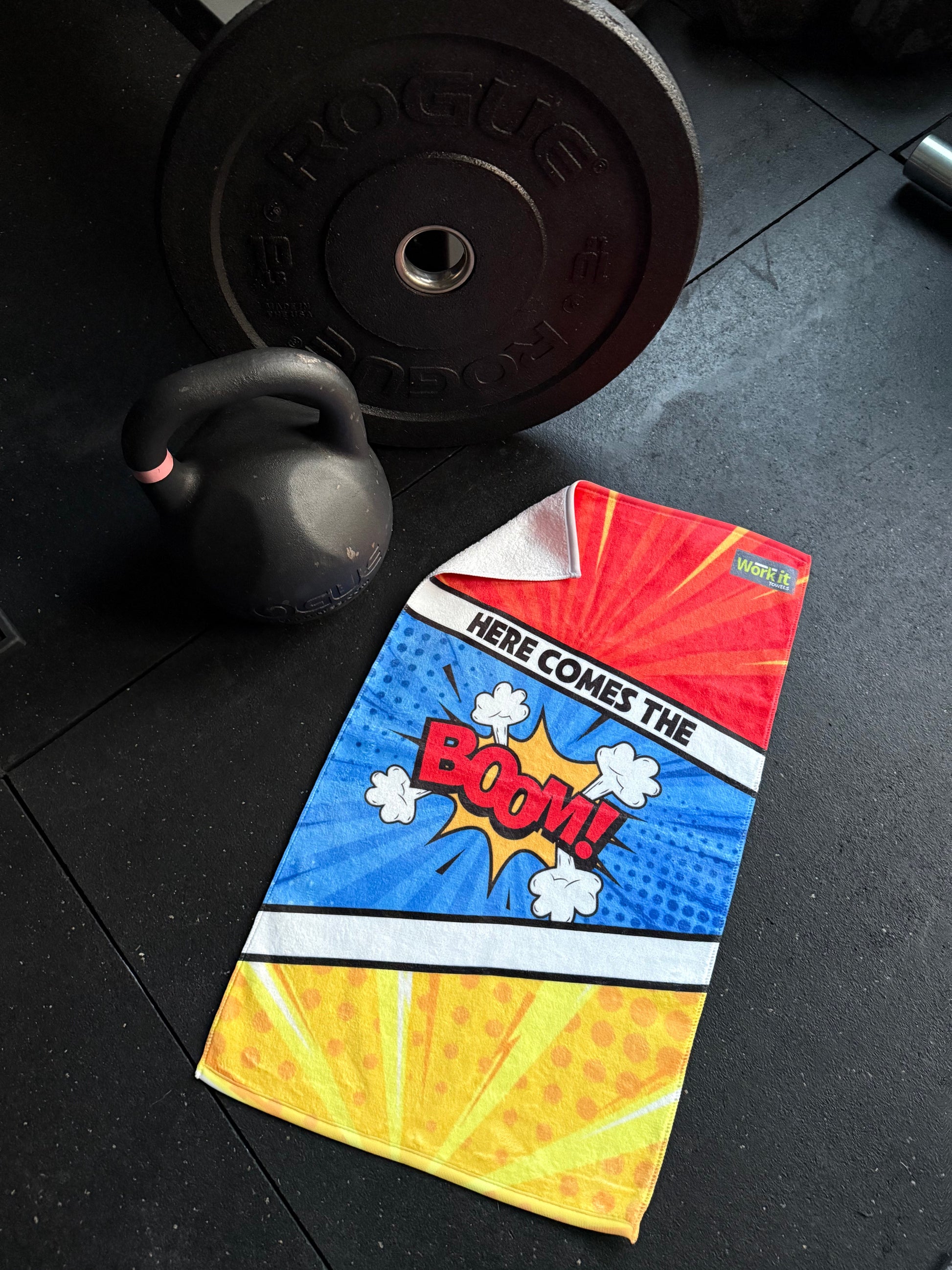 Colorful comic-style card with 'Here Comes the Boom!' text on a black floor with gym equipment.