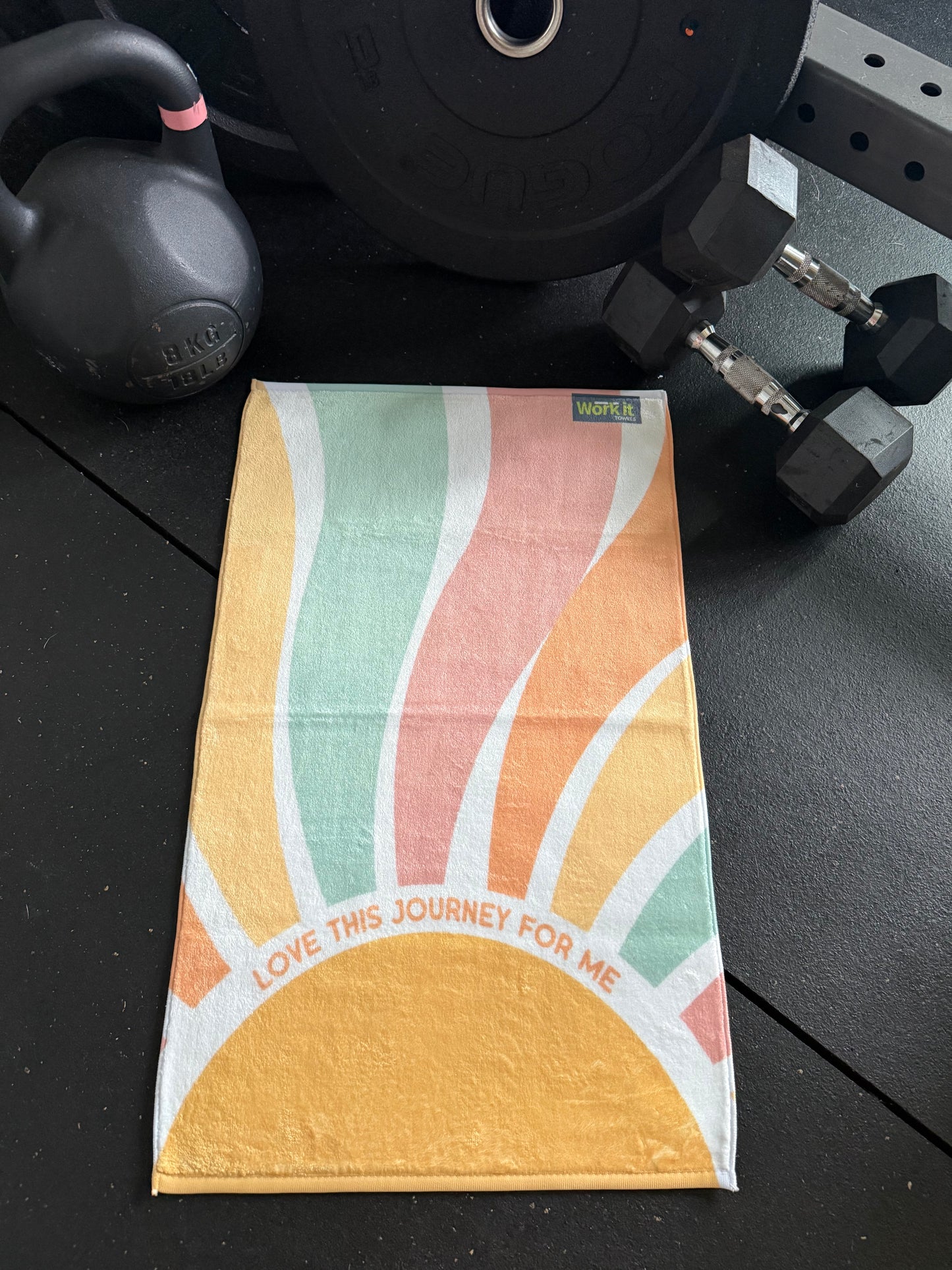 Colorful towel with abstract design on a black surface with gym equipment.