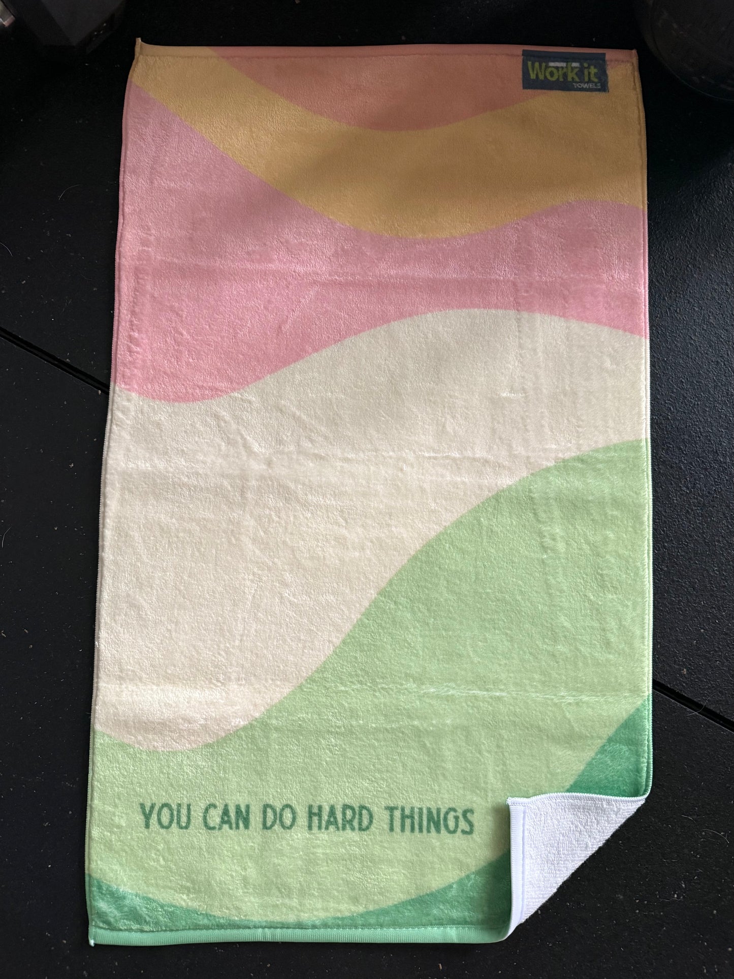 Colorful towel with wavy patterns and motivational text on a dark surface