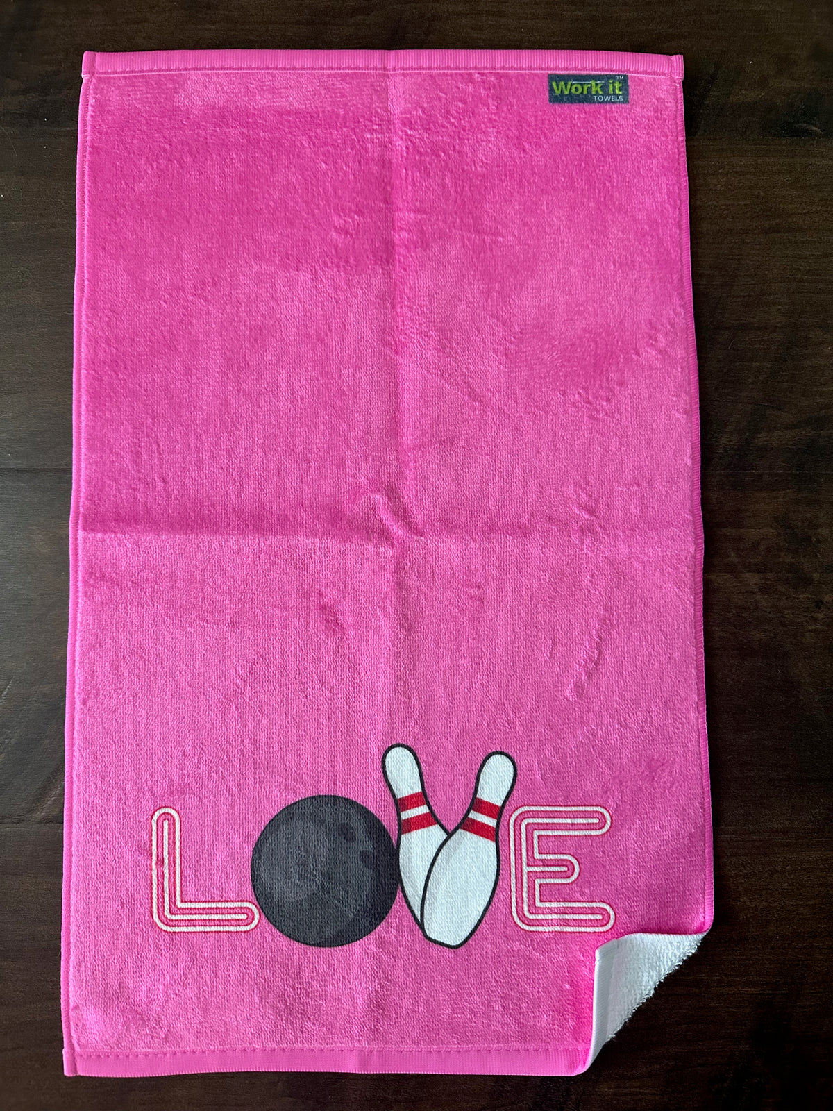 pink bowling towel with LOVE- the o is a bowling ball, and the v is 2 pins on hardwood floor
