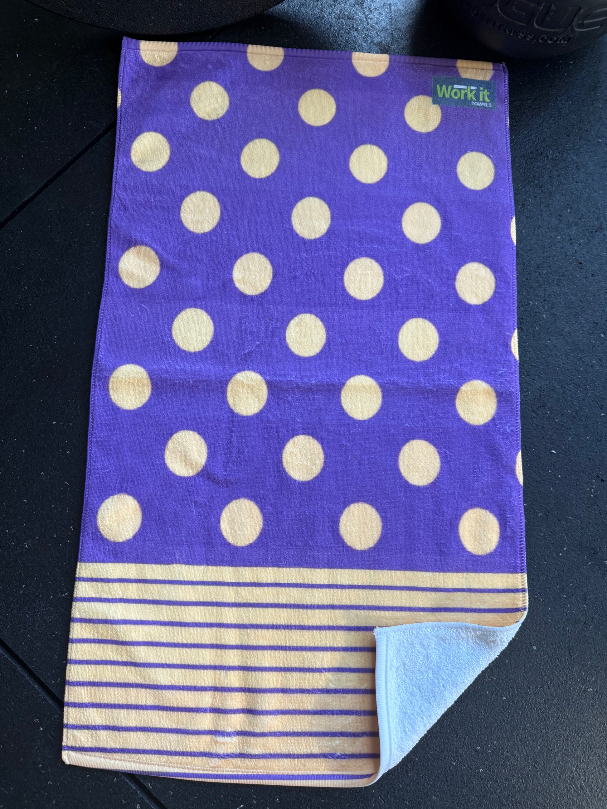 Purple towel with gold polka dots and stripes on a black surface