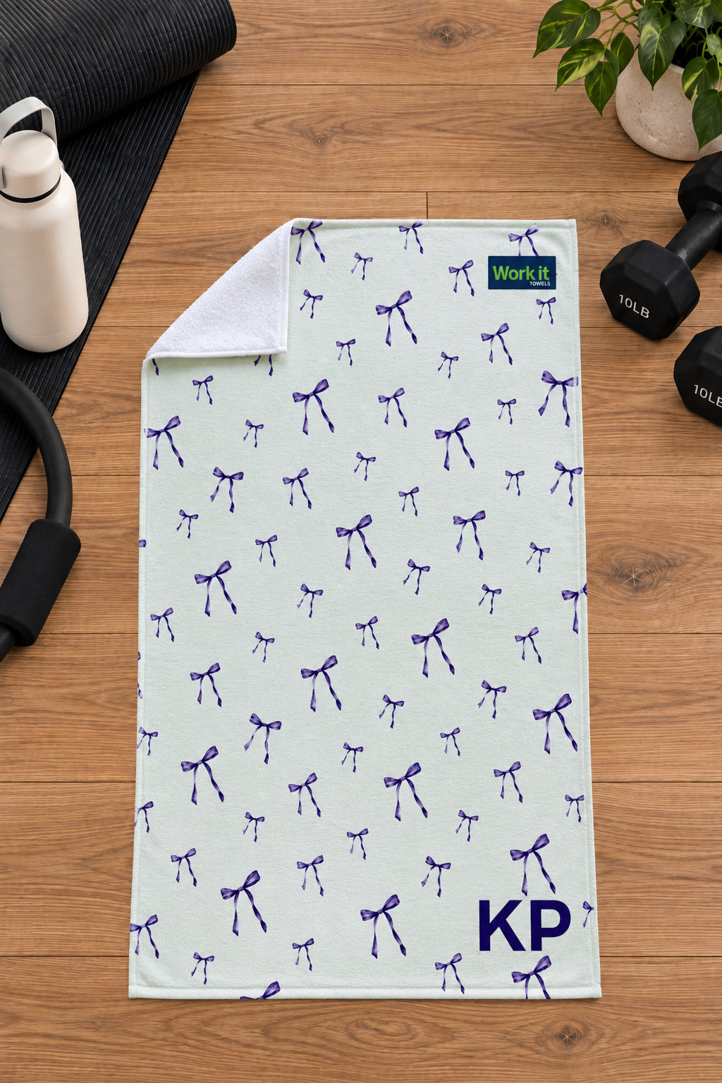 Purple bow personalized gym towel with custom 'KP' initials, one corner folded back to show the soft white terry reverse side.