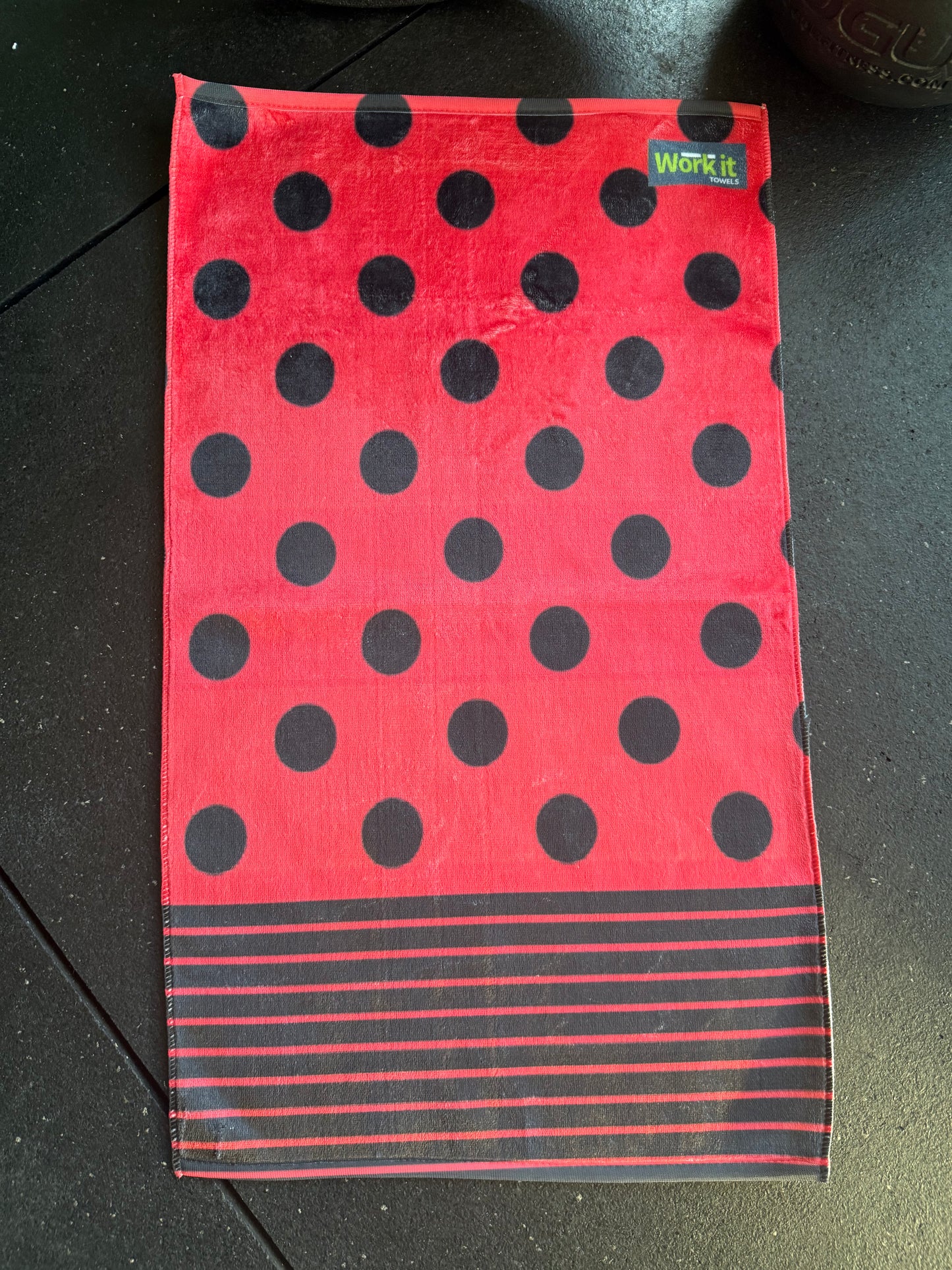 Red towel with black polka dots and stripes on a dark surface