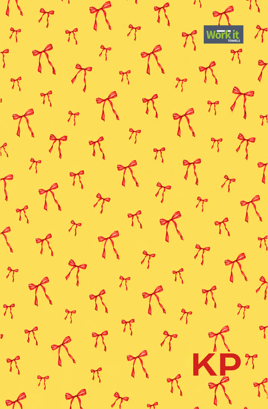 Yellow and red bow personalized gym towel: bright yellow with an all-over red bow print, Work It Towels tag, and custom 'KP' initials in red at the bottom right.